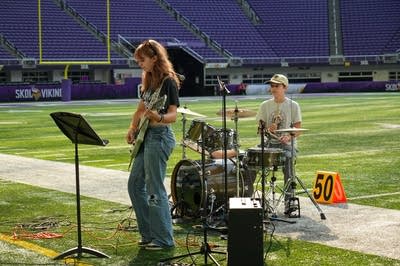 A rock band plays on the field at a football stadium.