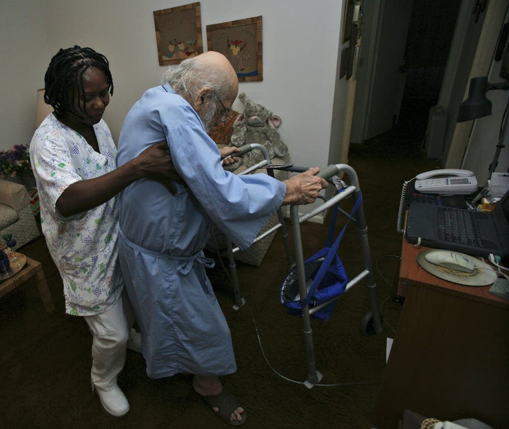 A nurse's aide helps an elderly patient