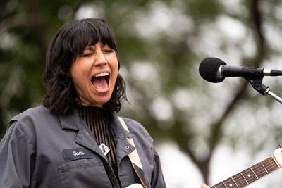 A musician sings and plays guitar at an outdoor venue