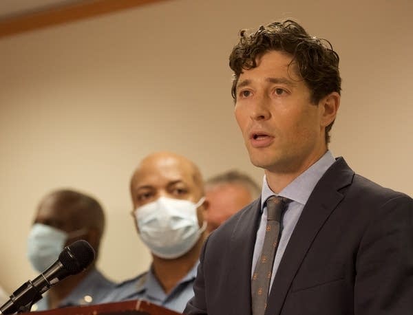 A man stands at a podium as others look on.