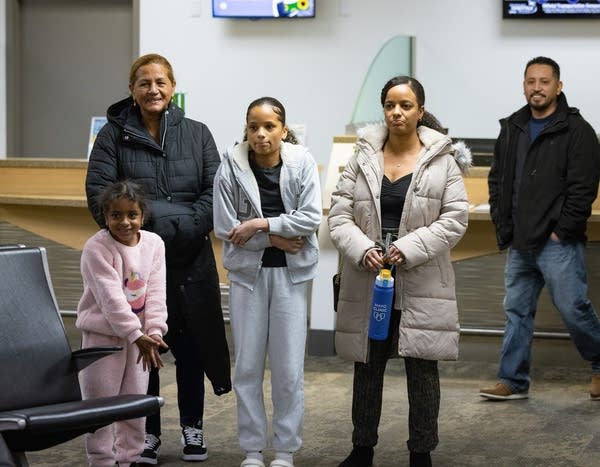 Two women and two girls wait in an airport.