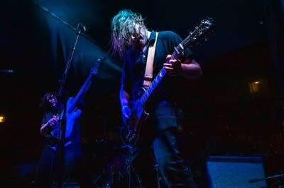 a rock band performing on an outdoor stage at night