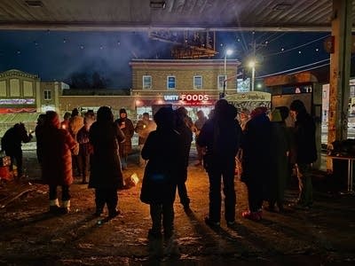 people standing outside with candles at vigil 