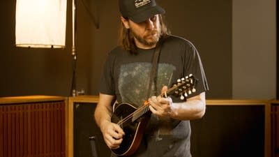 A musician plays mandolin in a recording studio