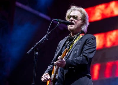 Daryl Hall singing on stage with an electric guitar
