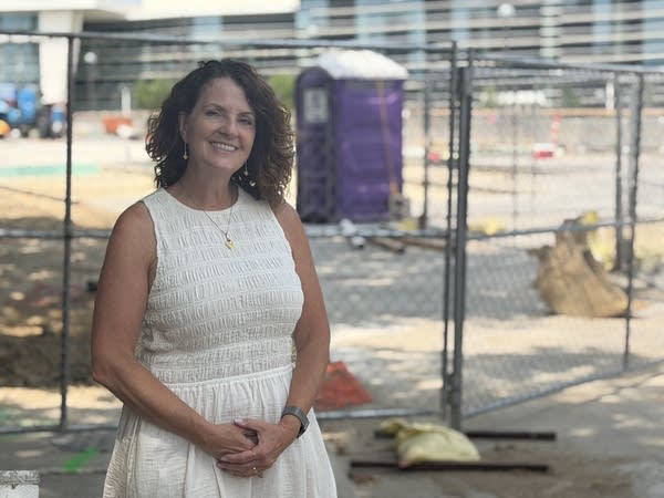 A woman in white dress smiling near a road closure