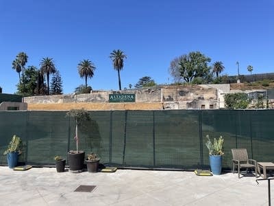 A closed off construction site; palm trees rise behind it.
