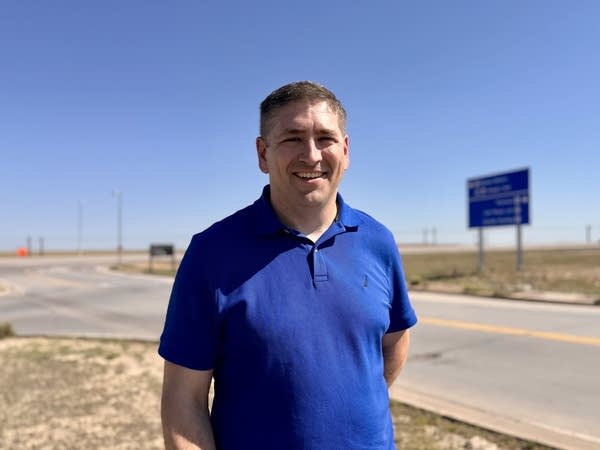 Man in blue shirt stands near airport.