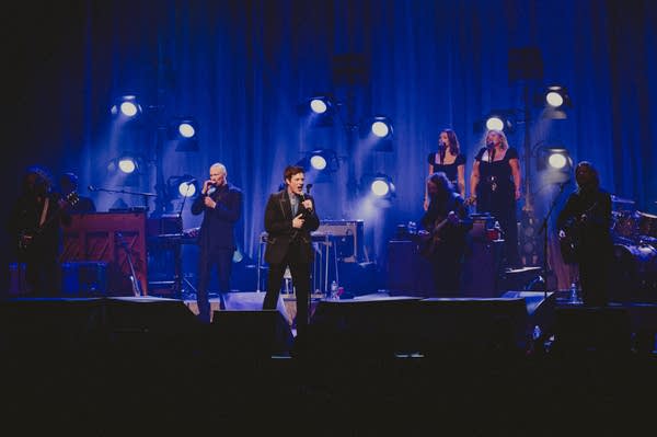 A band performing onstage in a large music venue
