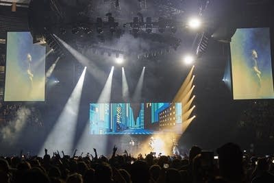 A rock band performing onstage in a large arena