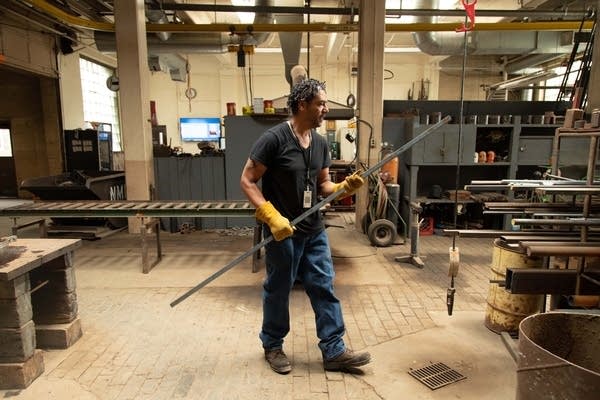 Nick Bounds walks through the shop with a rod of steel. 