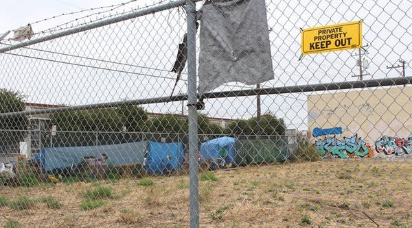 The belongings of people living on a sidewalk in East Oakland sprawl next to an empty lot on Aug. 24, 2018. Homeless advocate Candice Elder, 34, said vacant properties dot the area. “A lot of properties were vacant when I was growing up, and they are still vacant now,” said Elder, a native of the city. 