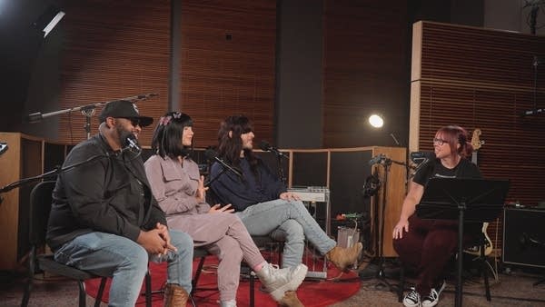 Four people have a conversation in a recording studio
