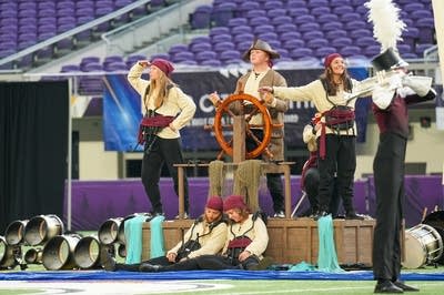 A marching band performs on the field of a football stadium.