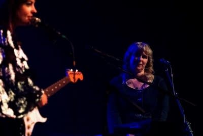 A keyboardist smiles as her bandmate speaks