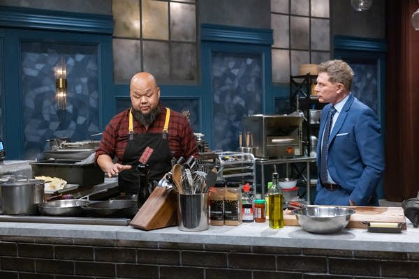 Two men stand behind a cooking counter