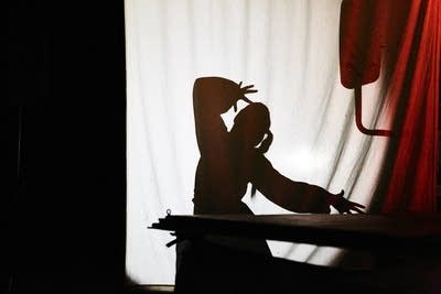 A silouette of an actor performing onstage