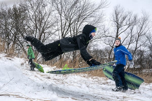 A teen flies in the air with a sled