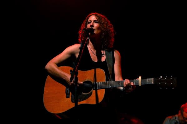 A woman sings and plays guitar onstage