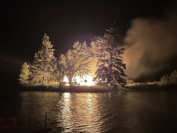 A fire burns a home surrounded by trees