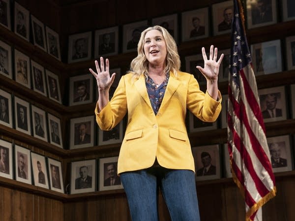 A woman holds her hands up while giving a speech.