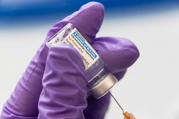 A close-up of a person loading a syringe with a vaccine. 