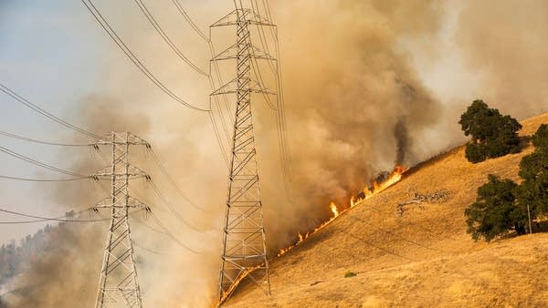 A backfire set by firefighters burns behind PG&E power lines as part of efforts to battle the Kincade fire in Healdsburg, California, on Oct. 26.