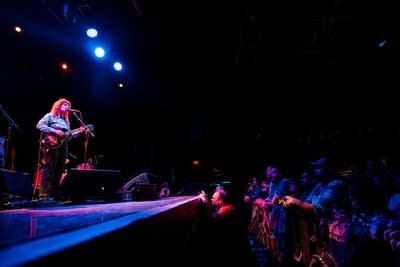 A woman sings and plays guitar onstage in a music venue