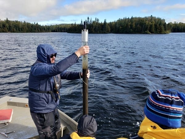 A person on a boat pulls up a sediment sample from a lake