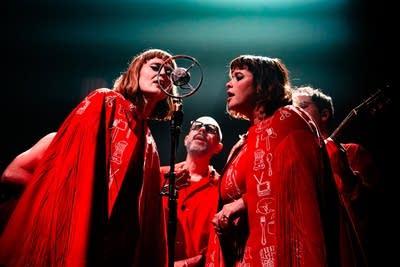 Five musicians gather round a ribbon mic for a semi-acoustic performance onstage