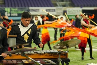 A marching band performs on the field of a football stadium.