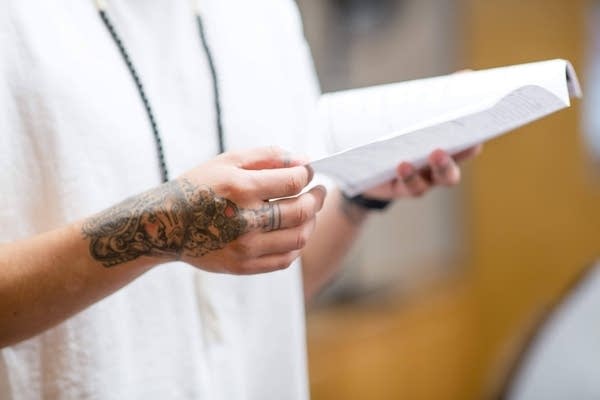close up of a man's arm holding a piece of paper 