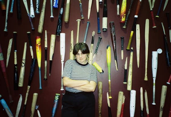 A person stands in front of a wall decorated with broken baseball bats