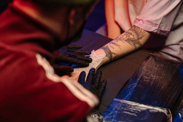 a tattoo artist placing a stencil on a client's arm