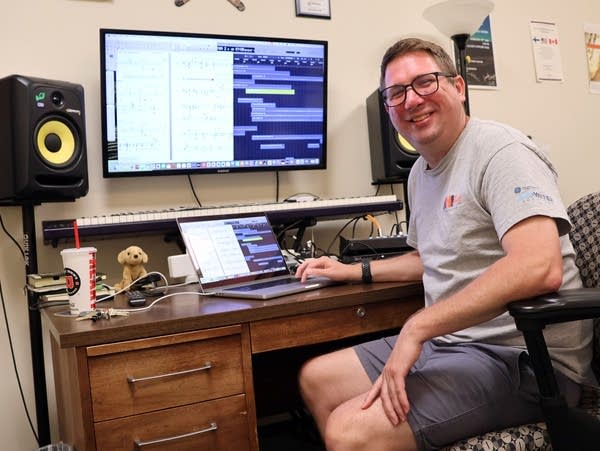 a man sits in front of a large computer screen