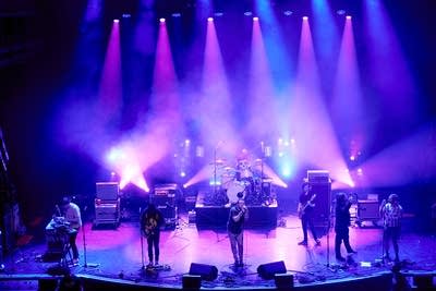 A seven-piece band performing onstage in a large music venue 