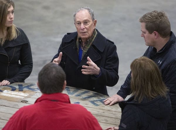 A group of people talk around a wooden spool table.