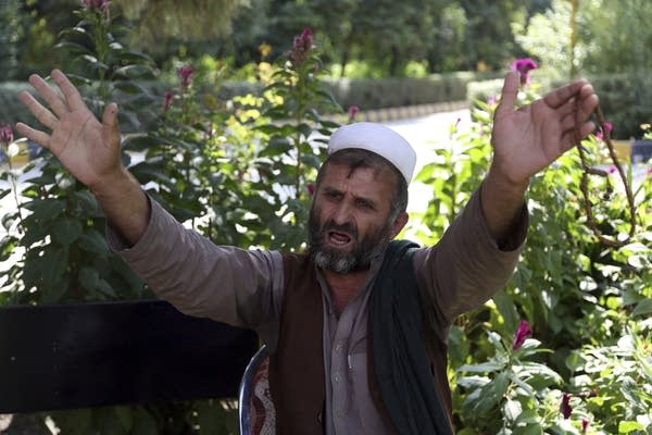 A man holds his arms up while talking
