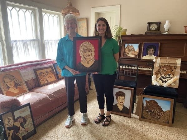 two women holding art piece