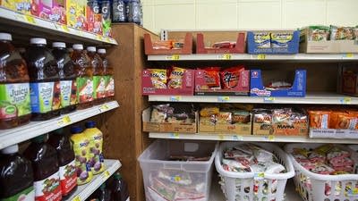 Bottles of fruit juice and boxes of instant ramen noodle sit on shelves.
