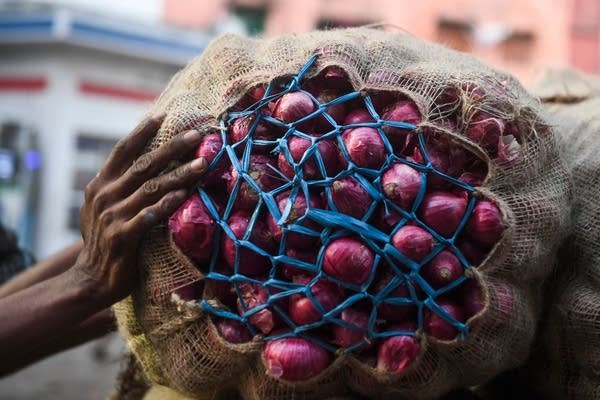 A labourer pushes a cart loaded with sacks of onions along a street in Kolkata.