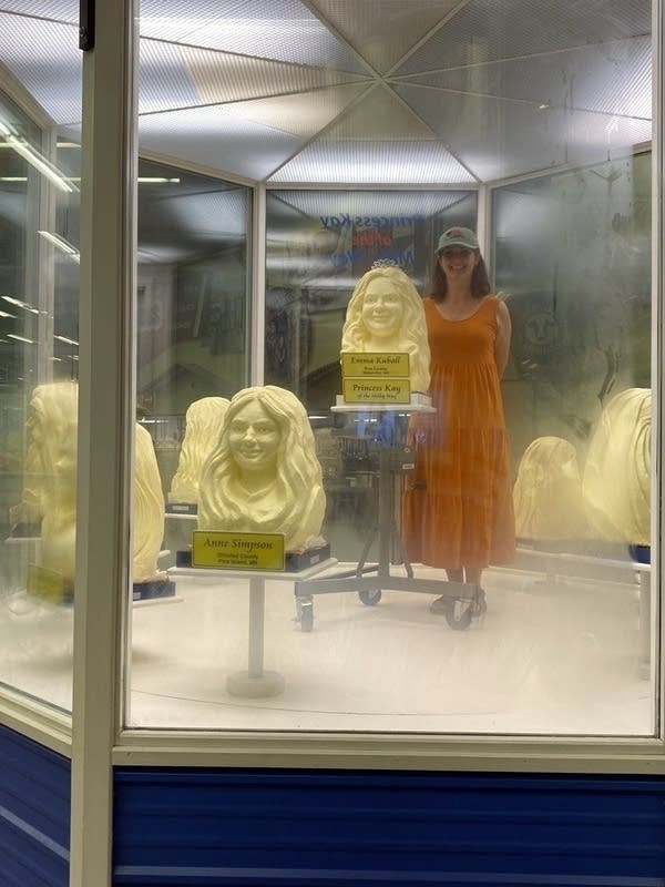 Woman posing next to butter sculptures 