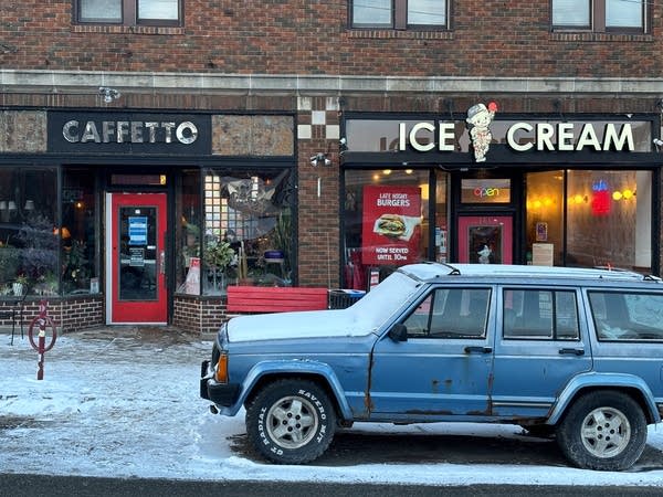 A blue SUV is parked in front of two restaurants, Cafetto and Bebe Zito.