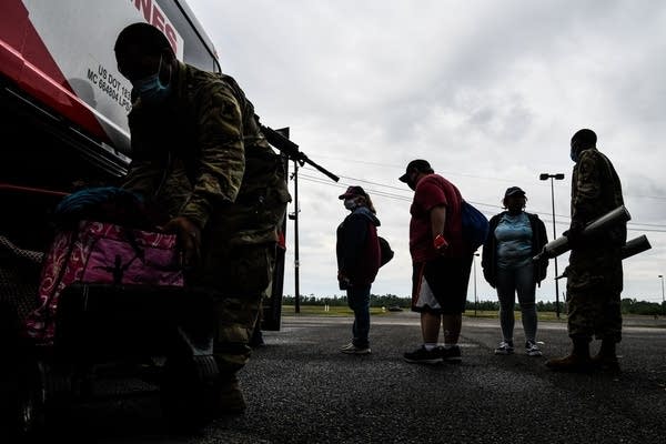 People stand outside of a bus.