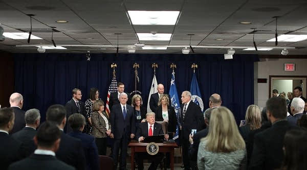 President Donald Trump signs two executive orders during a visit to the Department of Homeland Security with Vice President Mike Pence, Homeland Security Secretary John Kelly and other officials on Jan. 25 in Washington, D.C.