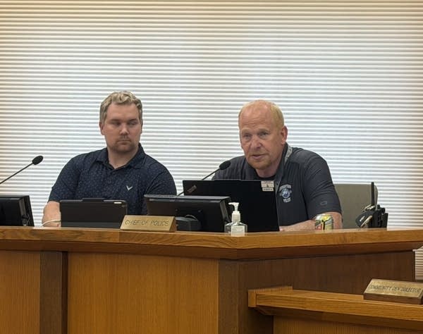 A police officer sitting a city council meeting