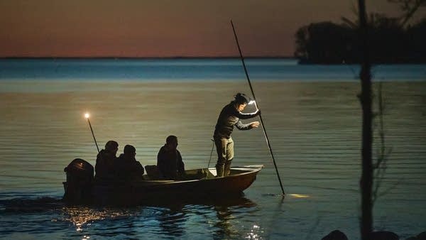 People fish on a lake after dark.
