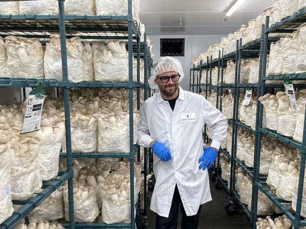 Andrew Carter stands in a lab coat surrounded by shelves of mushrooms