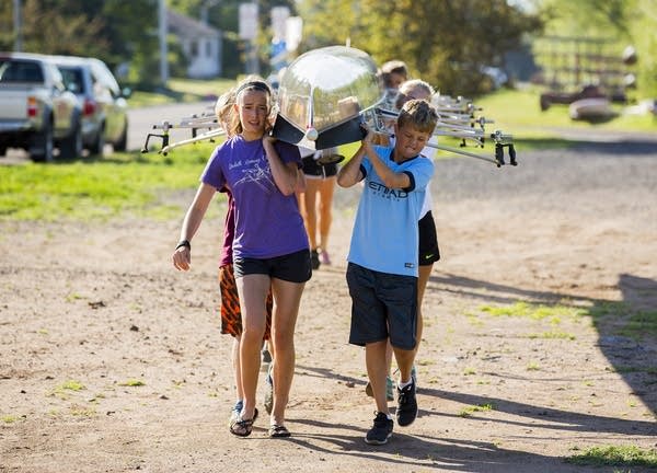 Kids carry an eight-man boat to the docks.