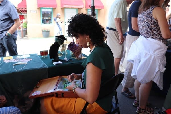 Yasmine Del Rosario sitting and beading at her booth